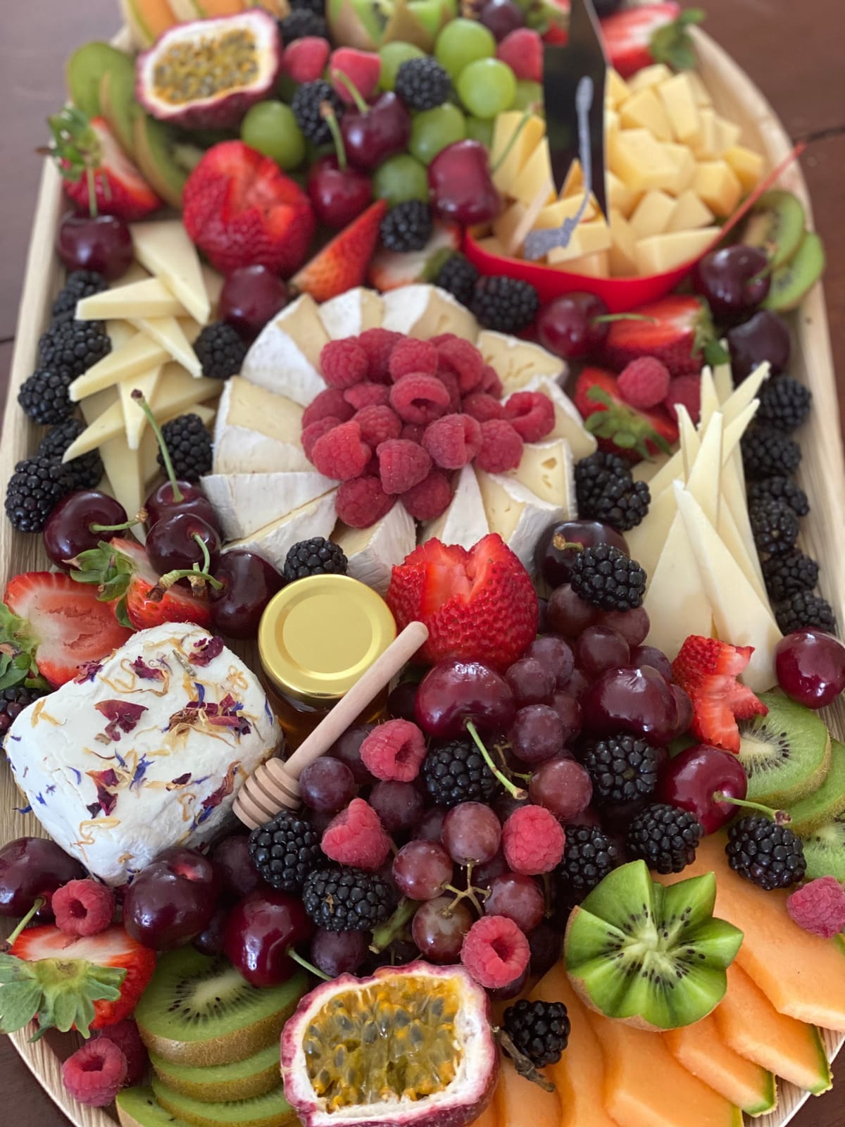 Large fruit and cheese board with seasonal fruit and artisan cheeses