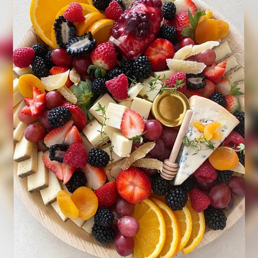 Seasonal fruit and cheese board with berries and honey