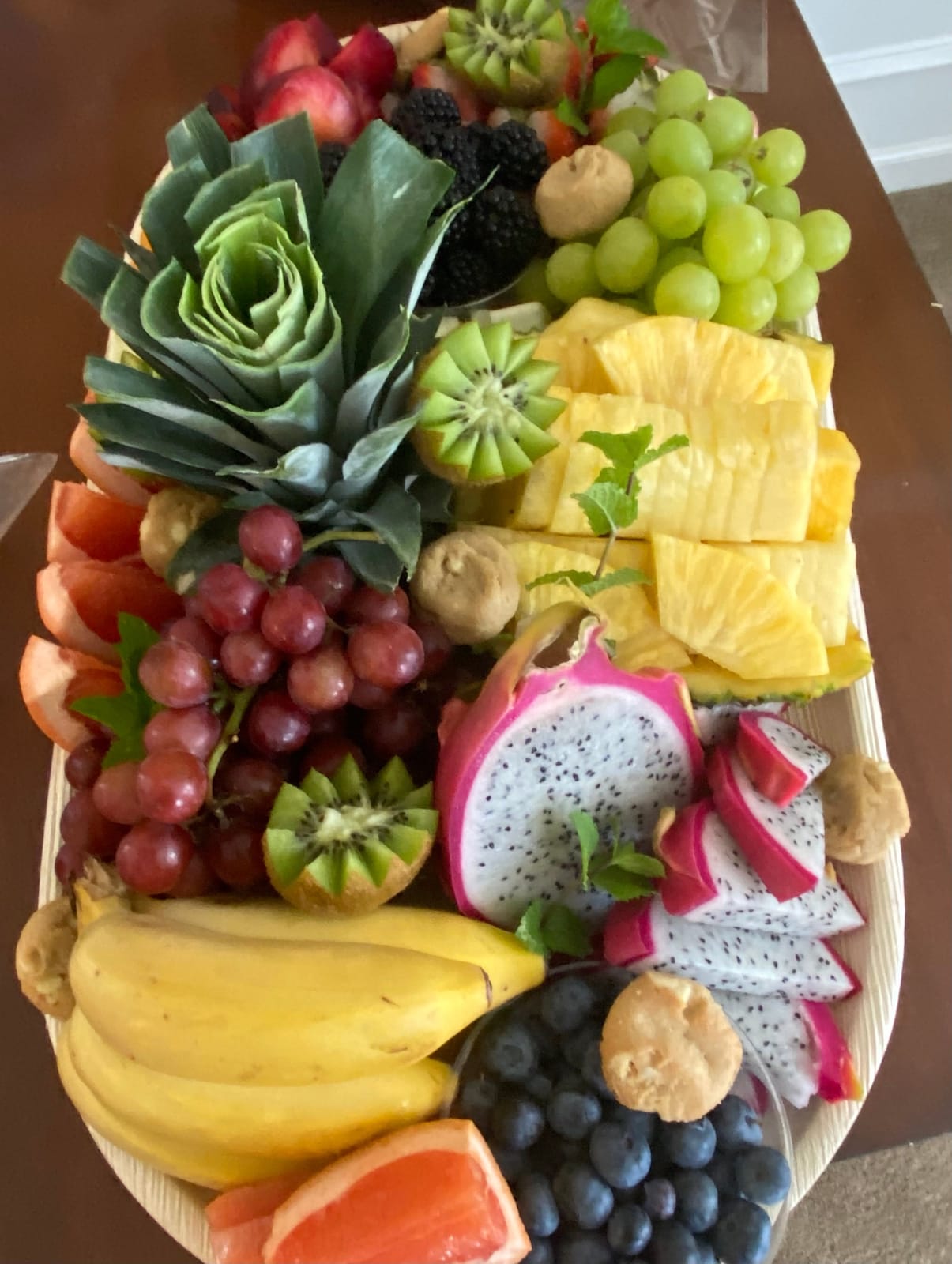 Carved seasonal fruit board with pineapple, grapes, kiwi and dragon fruit